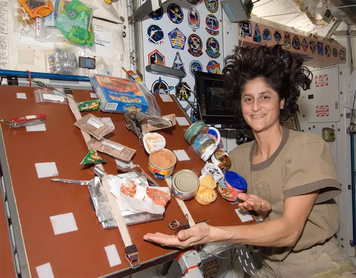Astronaut Sunita Williams zobrazuje jídlo, které připravila v modulu Udes 1 Udes 1